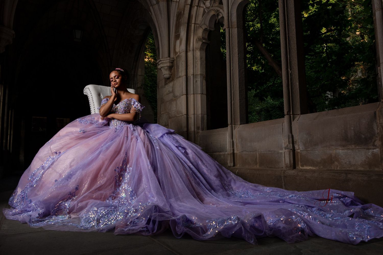Stunning purple gradient ball gown with cathedral train photographed in gothic archway setting creates dramatic silhouette.
