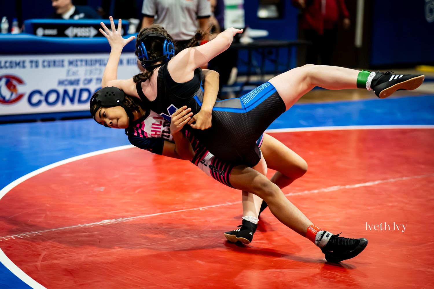 High school wrestlers compete on red wrestling mats during a tournament match.