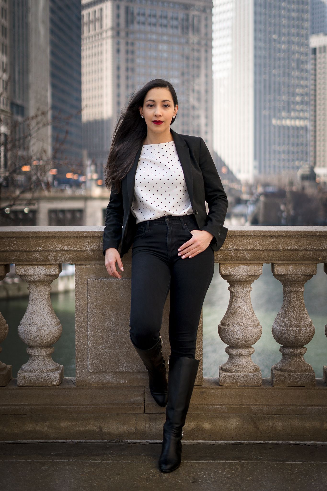 Professional urban portrait featuring black blazer and polka dot top against Chicago city backdrop.
