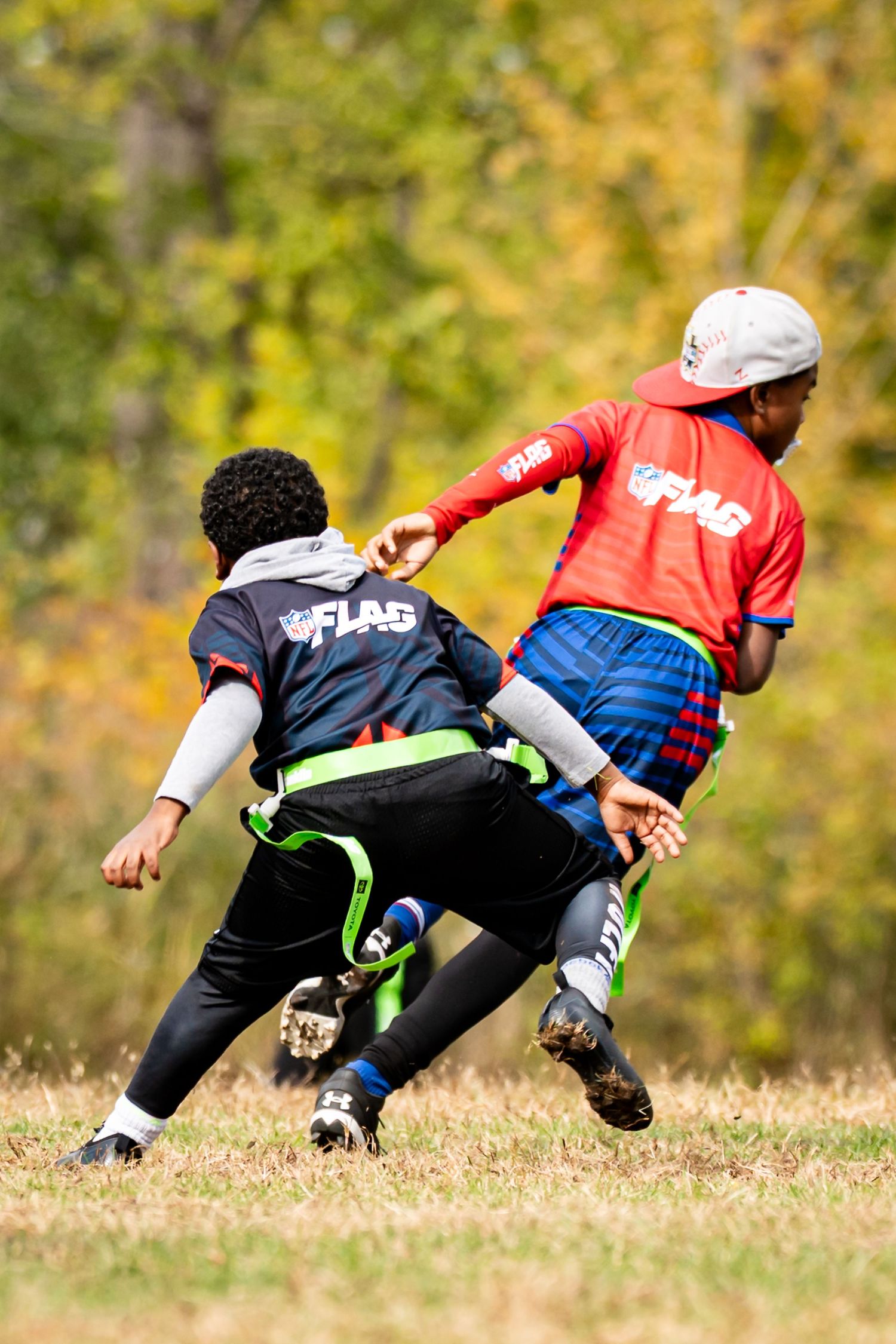 Players in red and black uniforms making diving plays during an intense flag football game.