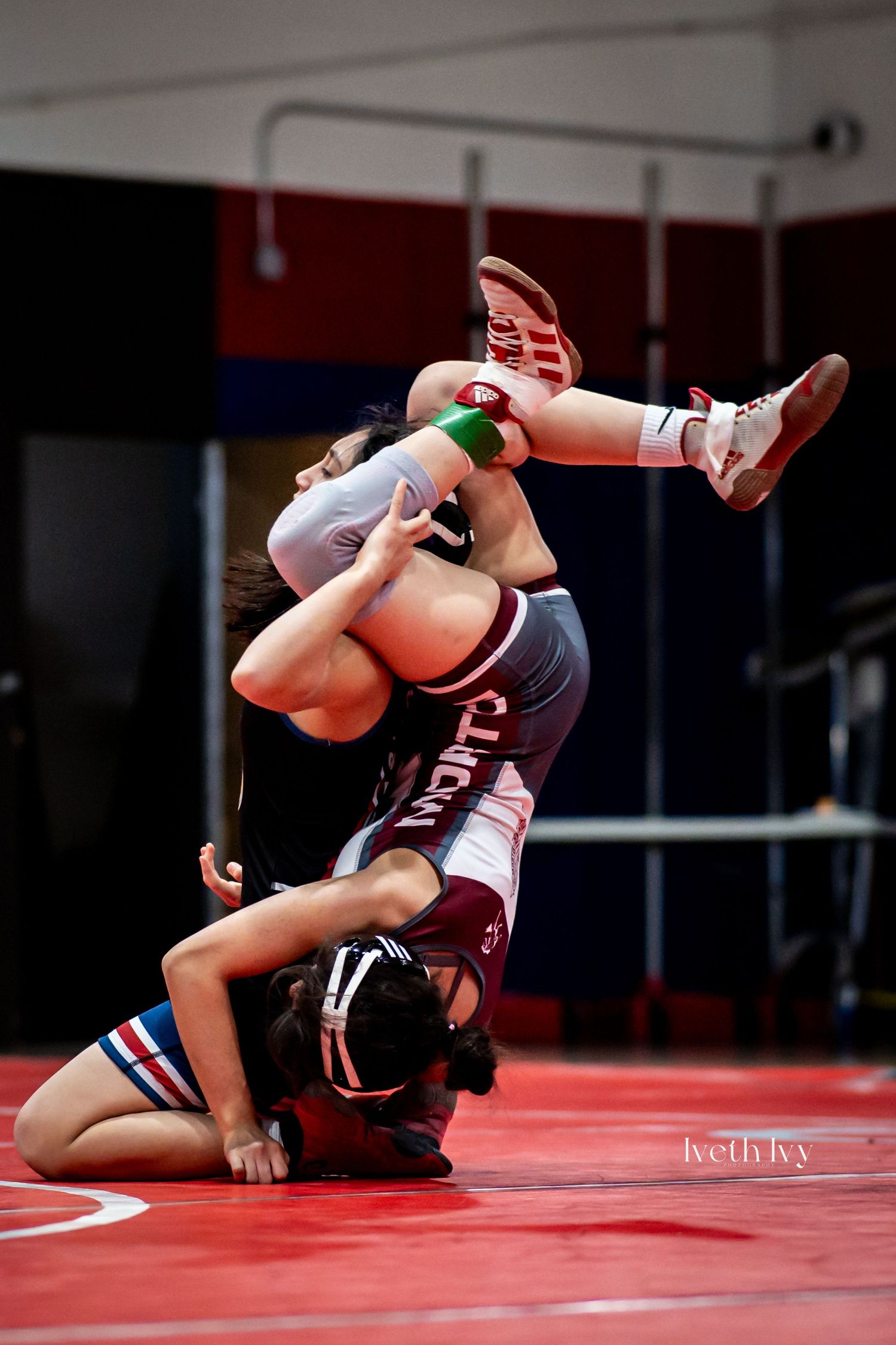 Wrestlers executing dynamic throws and takedowns during an intense match on red wrestling mats.
