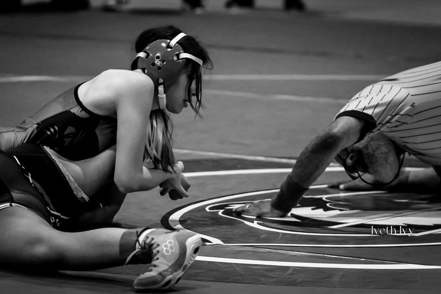 Two wrestlers grapple on a mat during an intense match with one attempting a takedown maneuver.