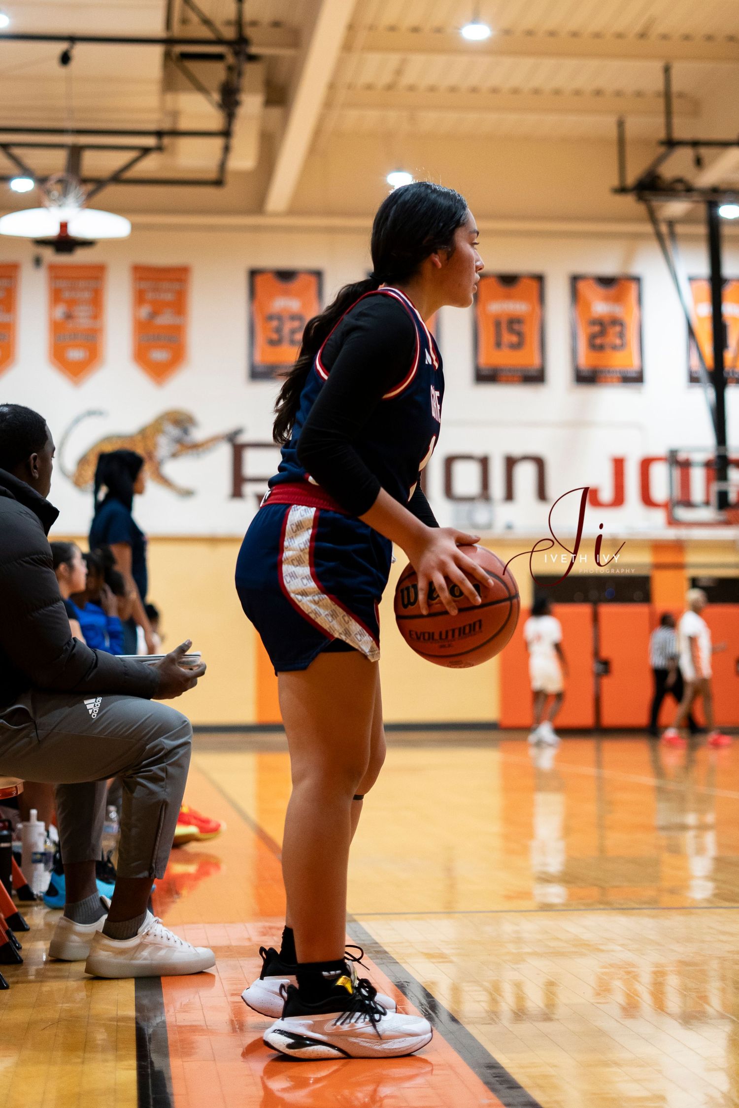 Basketball player dribbling on polished gym floor showing proper ball control technique during practice.