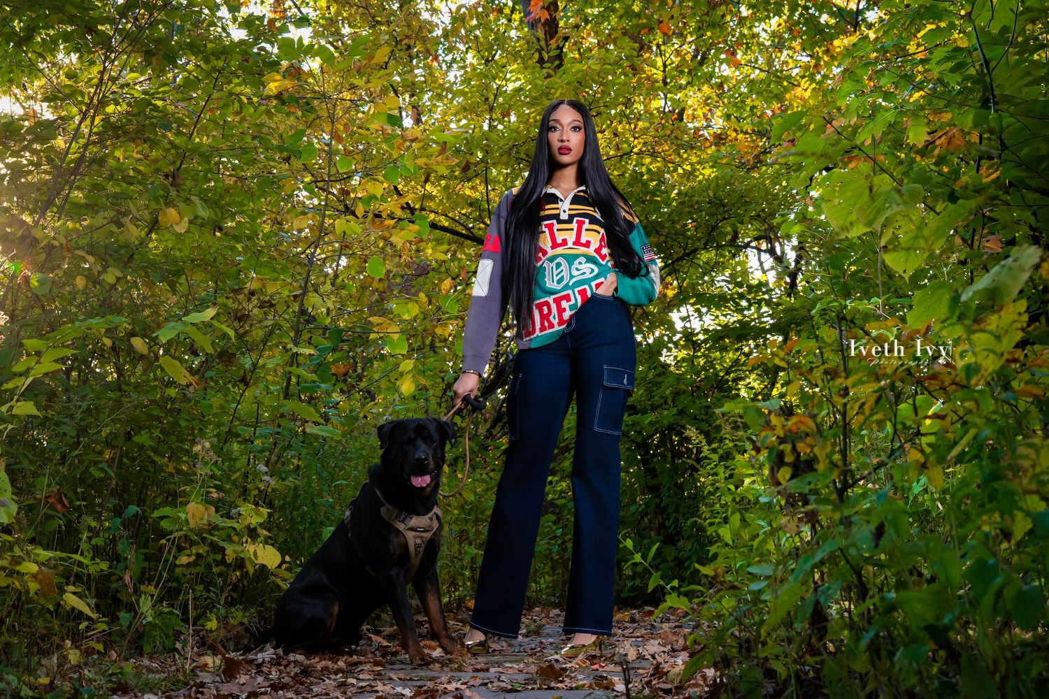 Person in a navy blue sweater poses against autumn foliage in an outdoor photoshoot setting.
