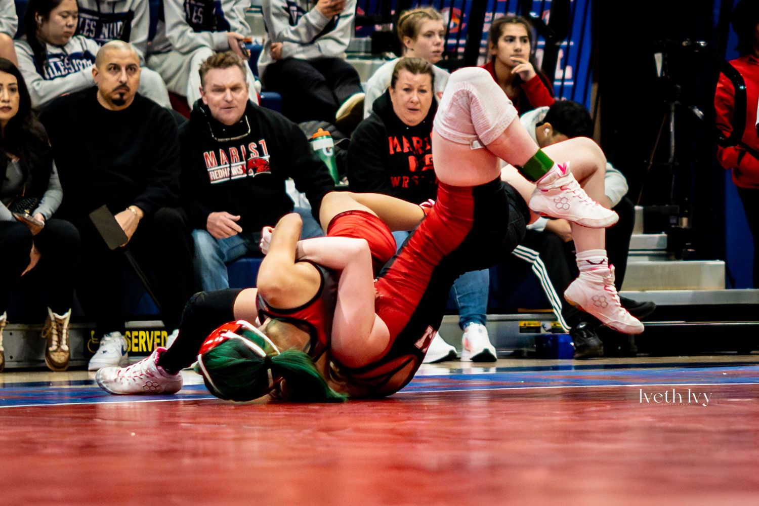 Wide angle view of multiple wrestling matches taking place simultaneously on mats with spectators watching.
