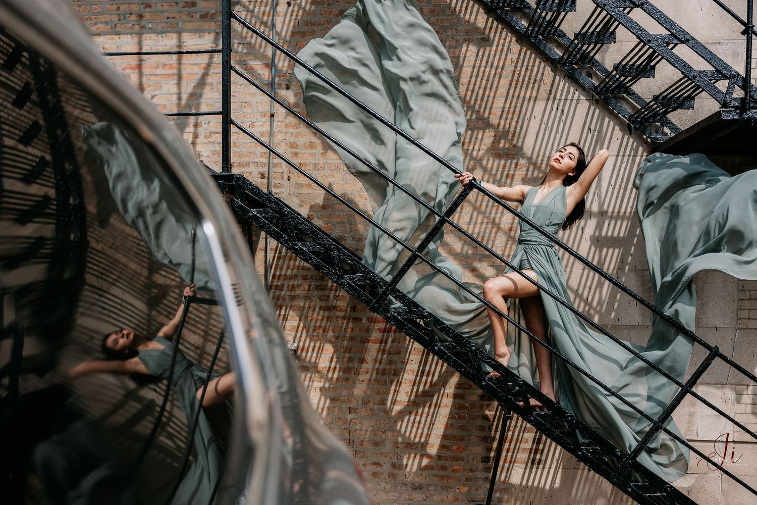 Person in casual attire poses against brick wall interior with industrial staircase in geometric photography composition.