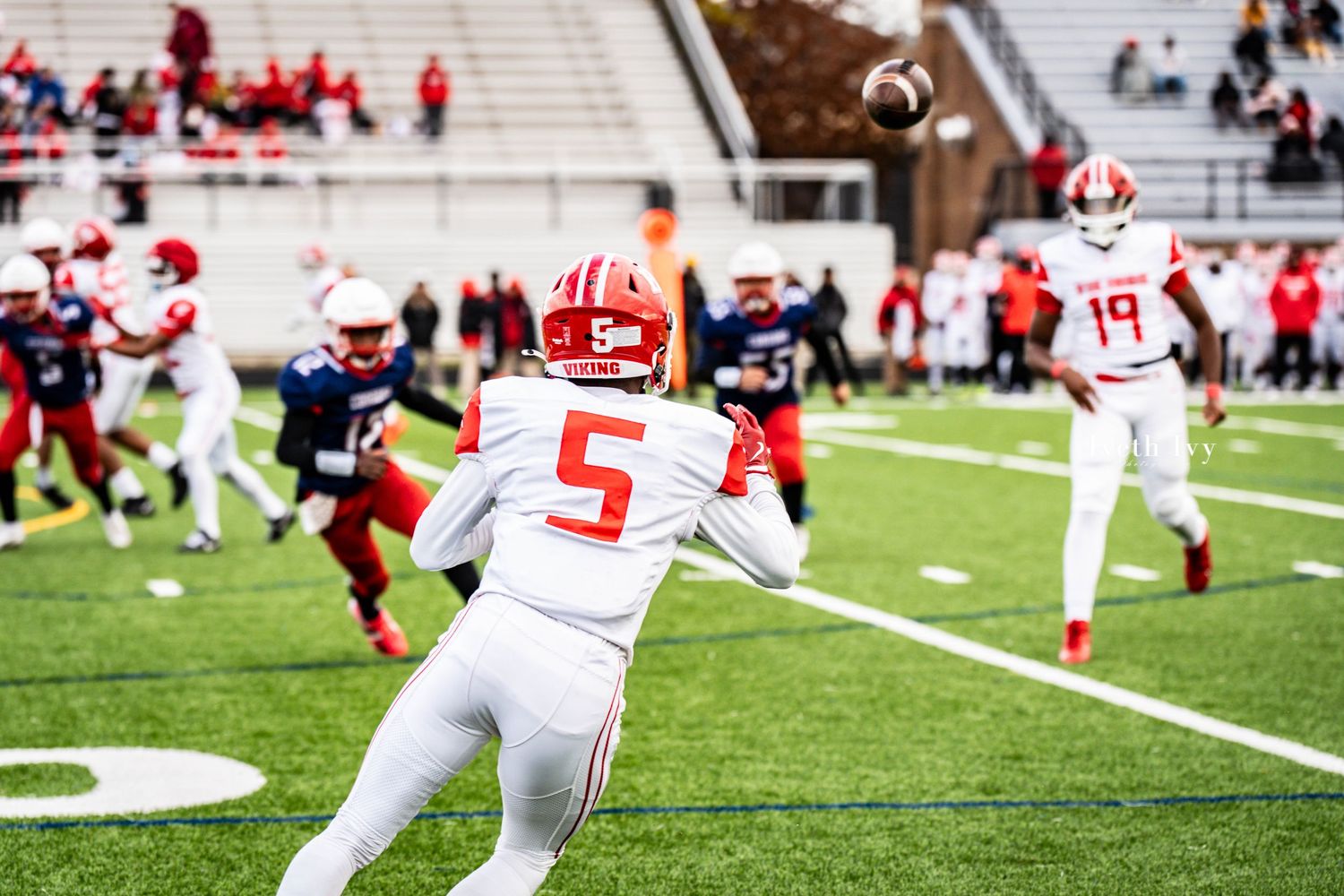 Multiple football players from opposing teams collide during a competitive play on the gridiron.