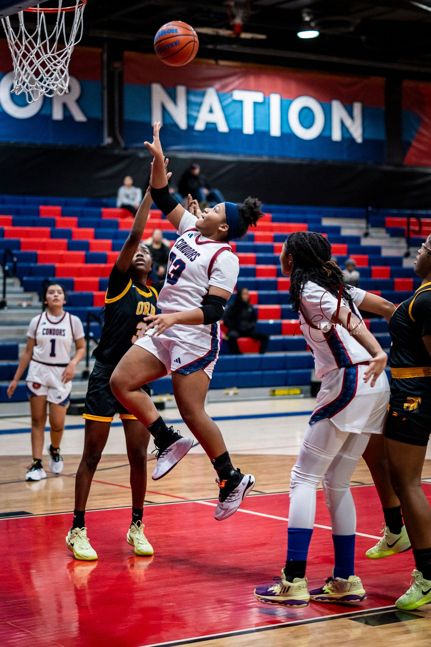 Basketball players compete for a rebound during an intense game with Nation signage visible in the background.