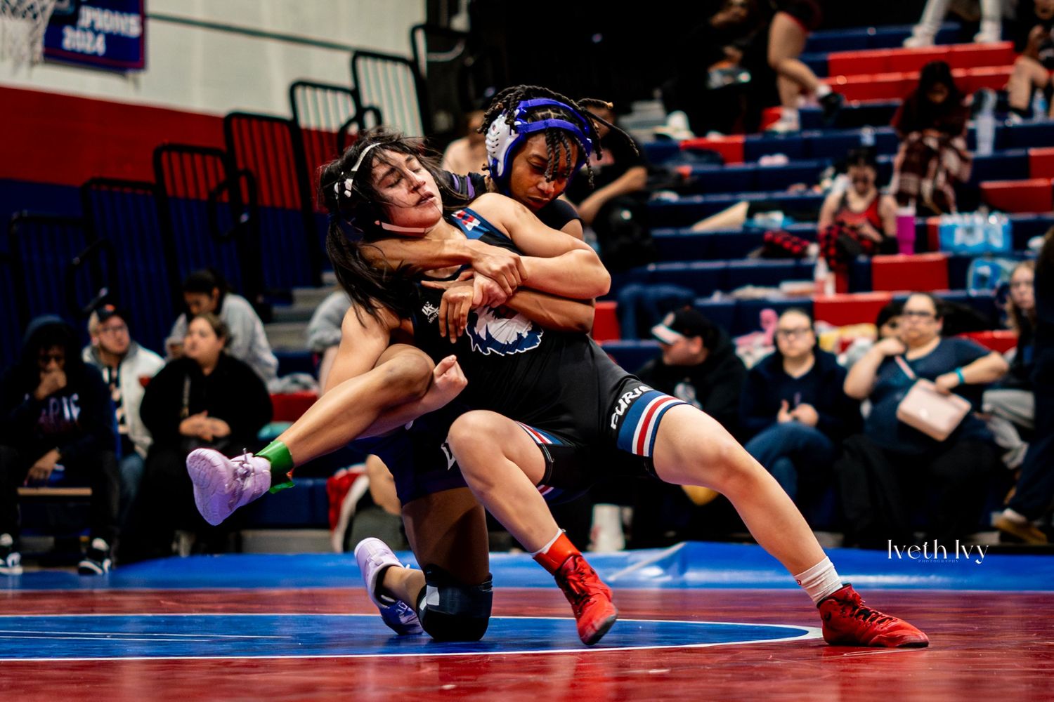 High school wrestlers compete in a tournament match on a professional wrestling mat.