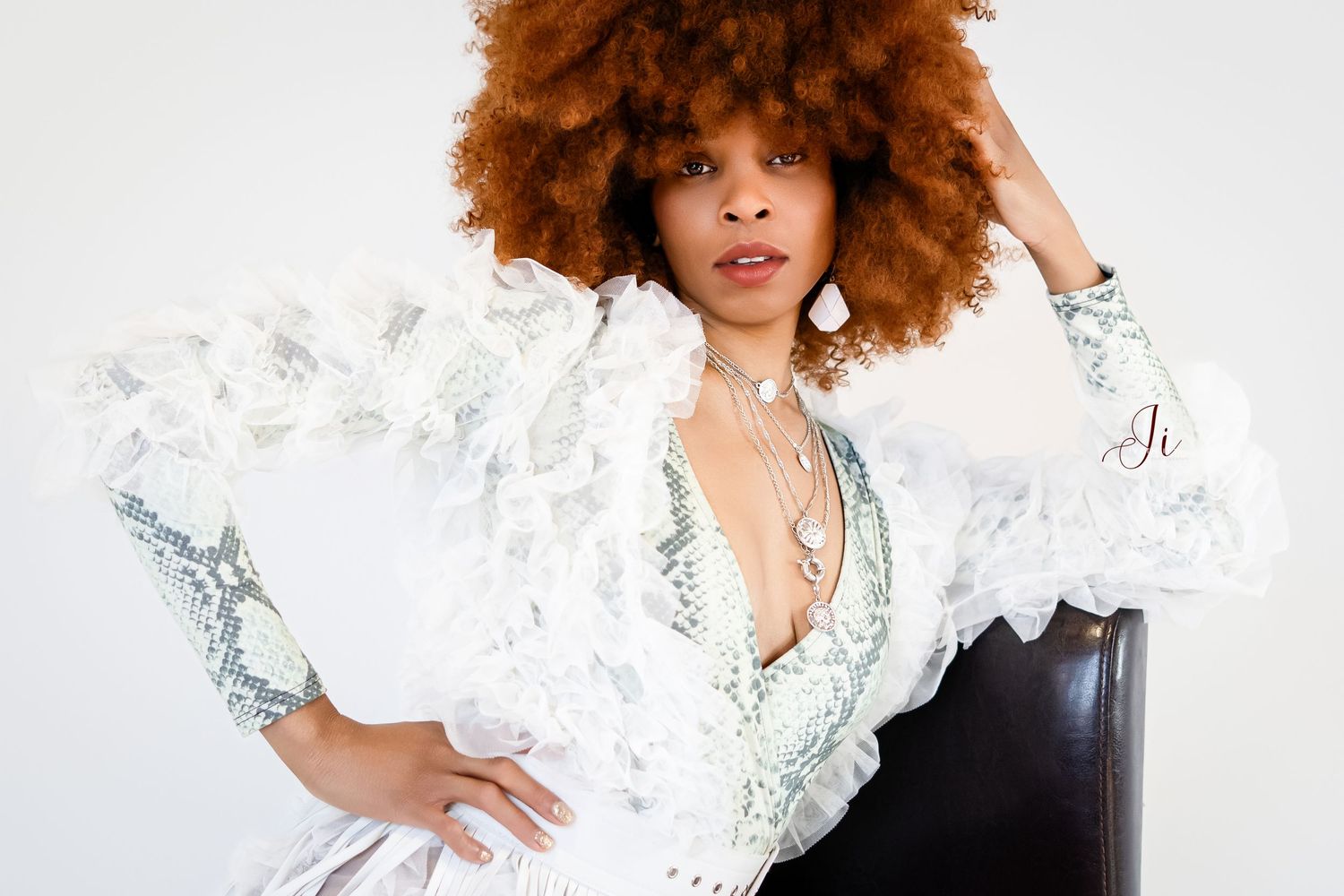A model wearing a dramatic white ruffled top with voluminous sleeves poses elegantly against a light background.