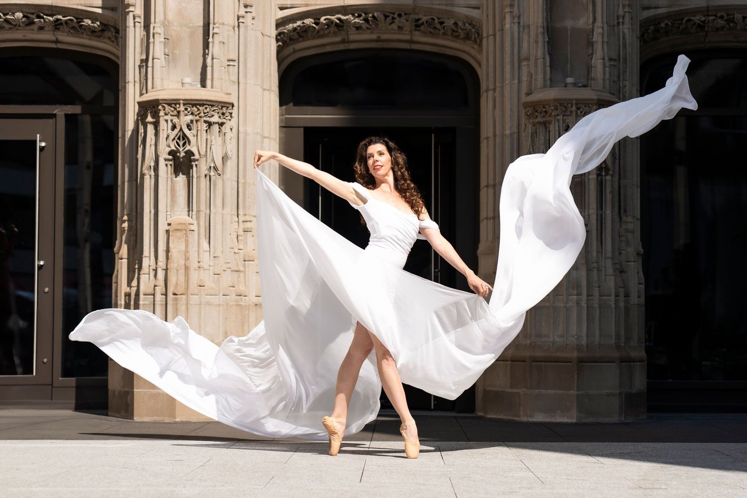 Flowing white fabric billowing dramatically against historic stone architecture.