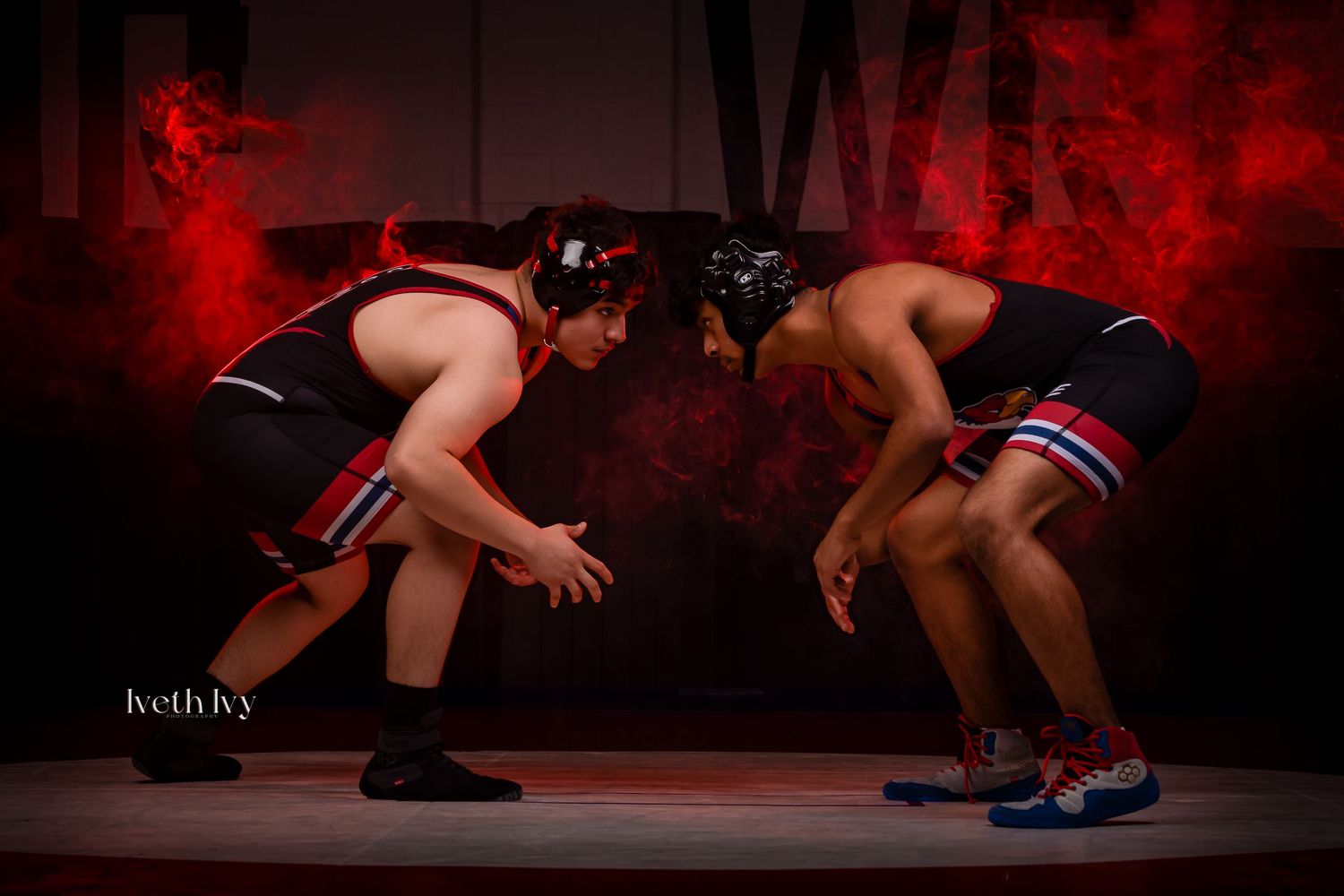 Two wrestlers in a competitive match grappling on a red-lit mat during an intense wrestling competition.