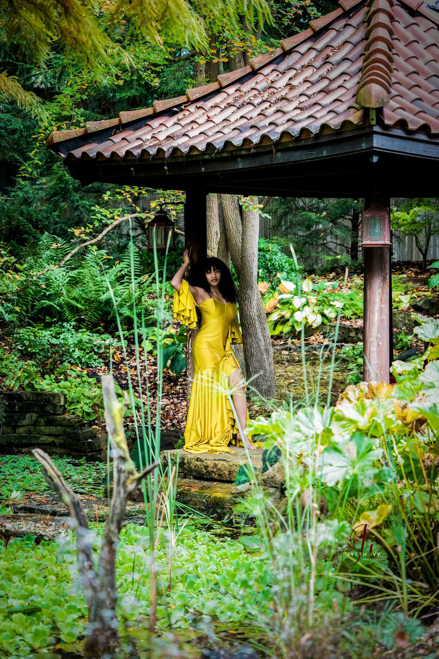 Yellow flowing dress in Japanese garden setting with pagoda roof and lush greenery.