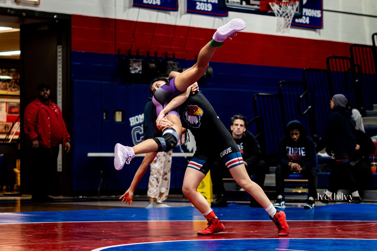 Wide angle view of multiple wrestling matches taking place simultaneously in a gymnasium.
