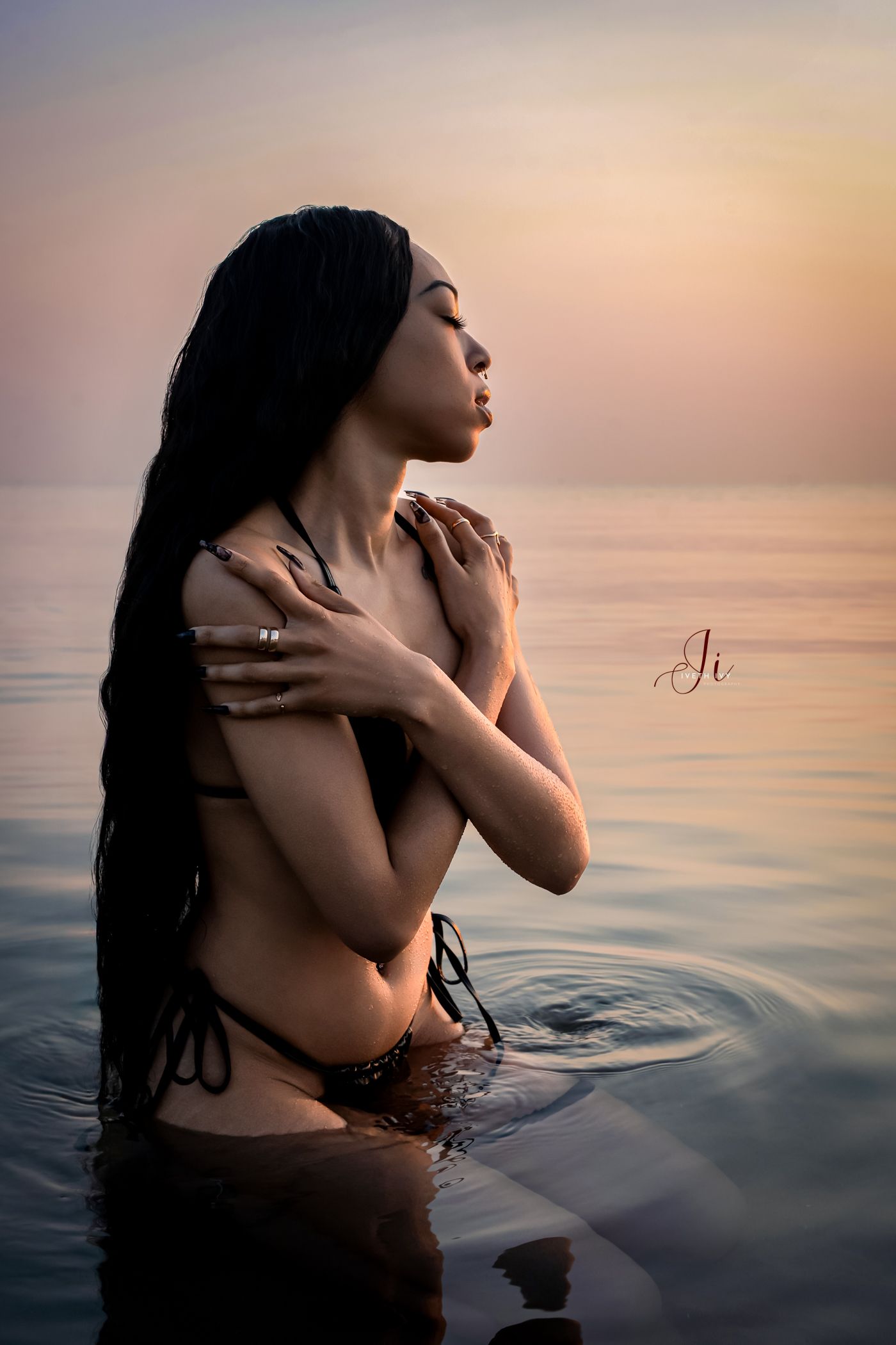 A silhouetted figure emerges from tranquil waters during golden hour, creating a sensual and artistic composition.
