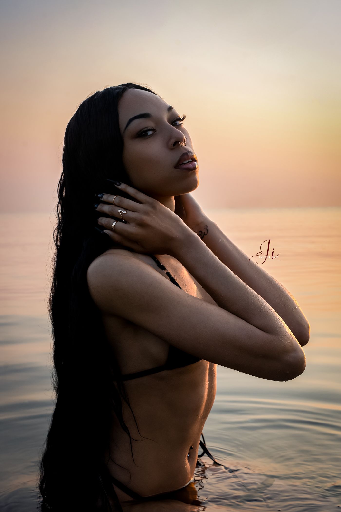 Silhouette of a person in water during golden hour sunset with reflective ripples on ocean surface.