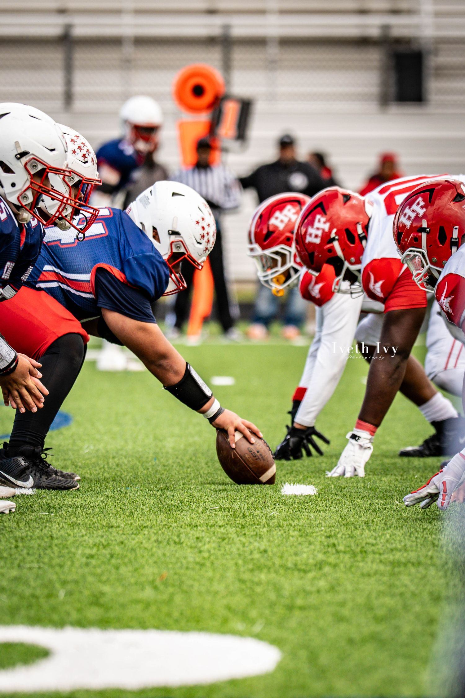 Football players from opposing teams line up at scrimmage during an intense game on artificial turf.