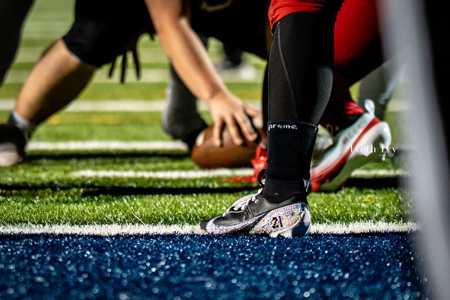 Close-up shot of football players' cleats and feet on artificial turf during a game.