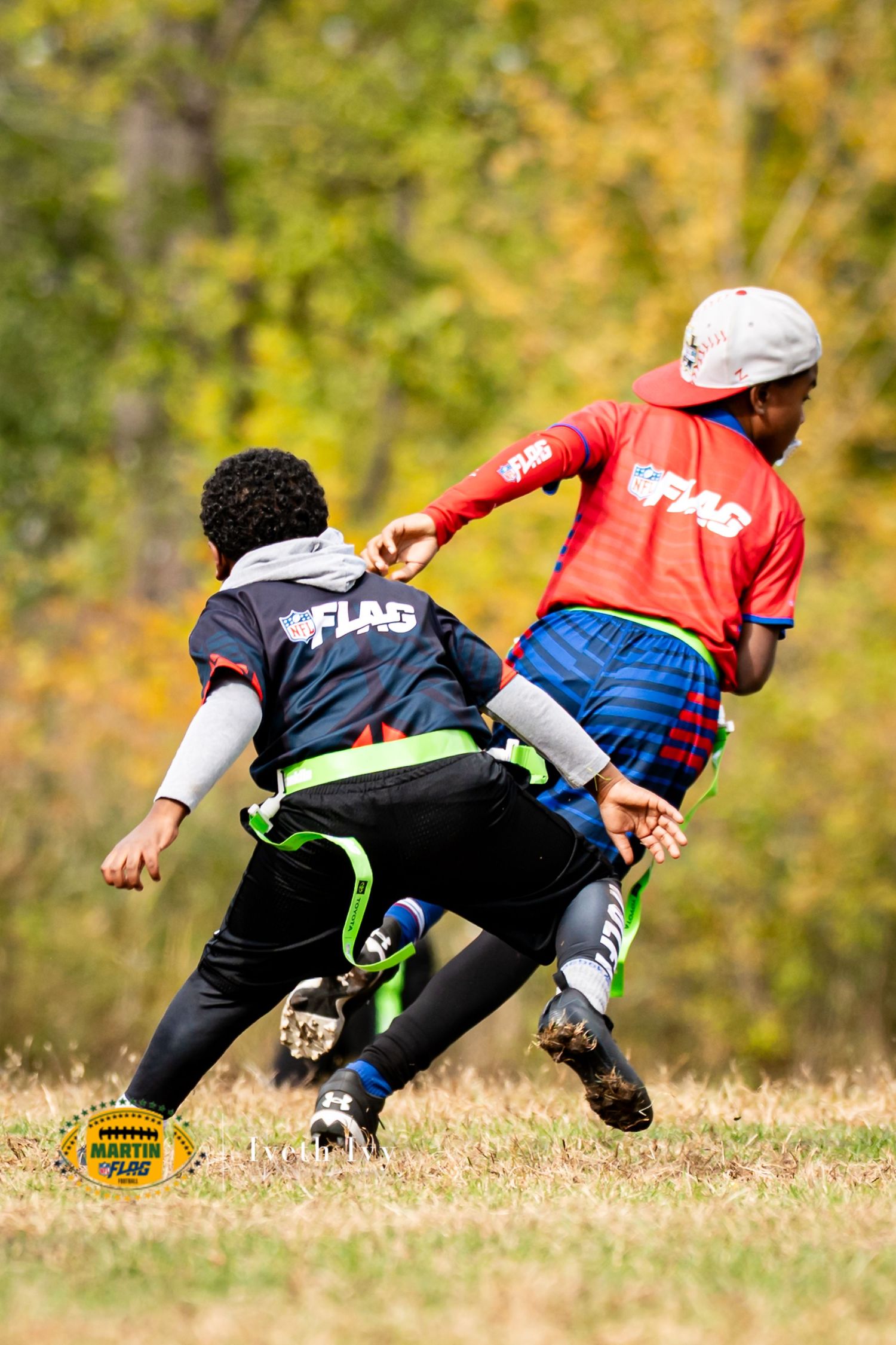Two players dive for the football during an intense flag football match on a sunny autumn day.