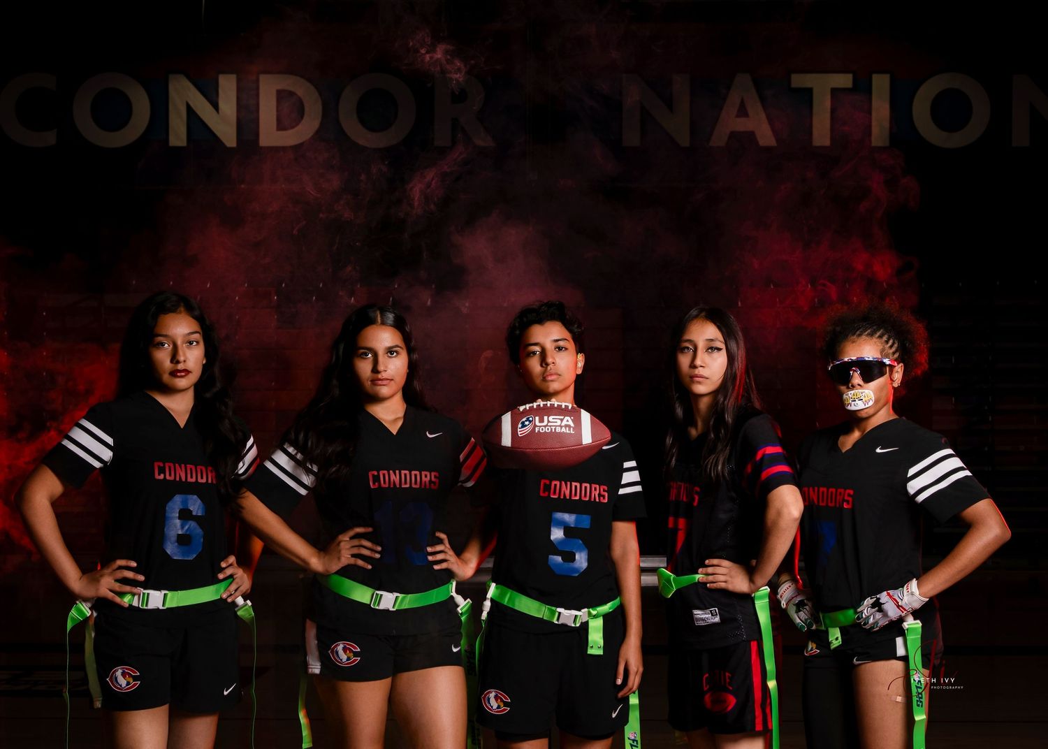 A group of athletes pose together in black uniforms with glowing green accents for a team photo.