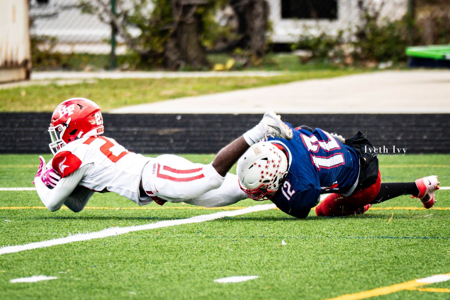 Football players lying on the turf field after a play during a competitive match.