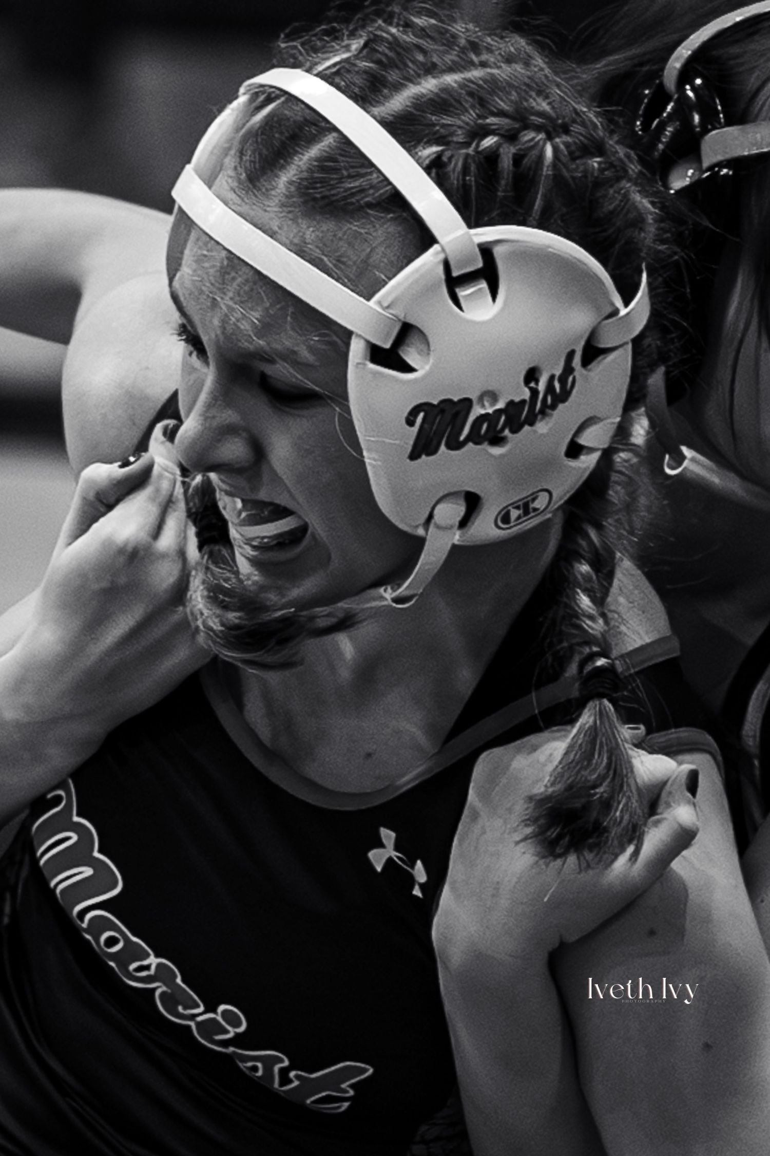 Black and white image of wrestlers wearing protective headgear during competition.