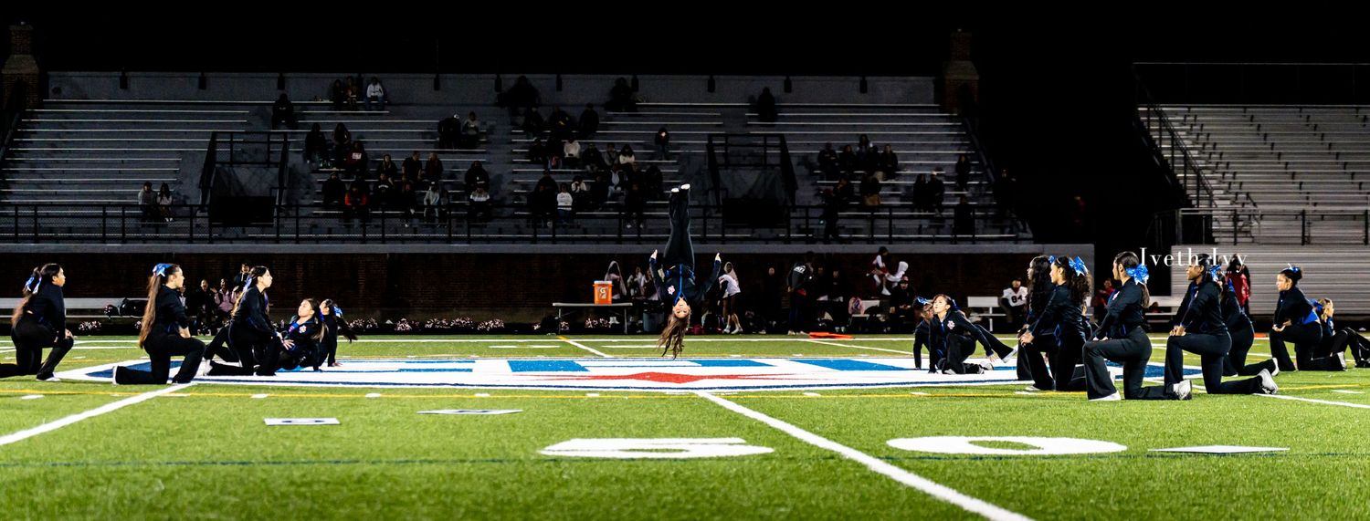 Panoramic view of a football stadium with players practicing on the field during evening hours.