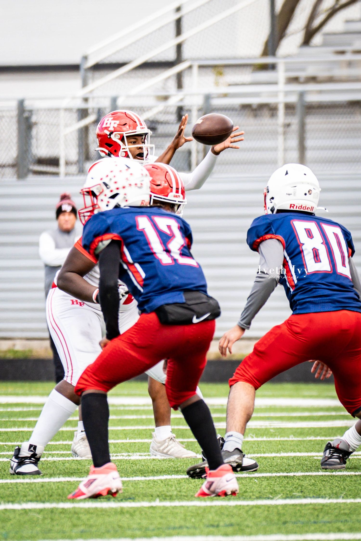 Football offensive line crouches in formation at the line of scrimmage wearing red and blue uniforms.