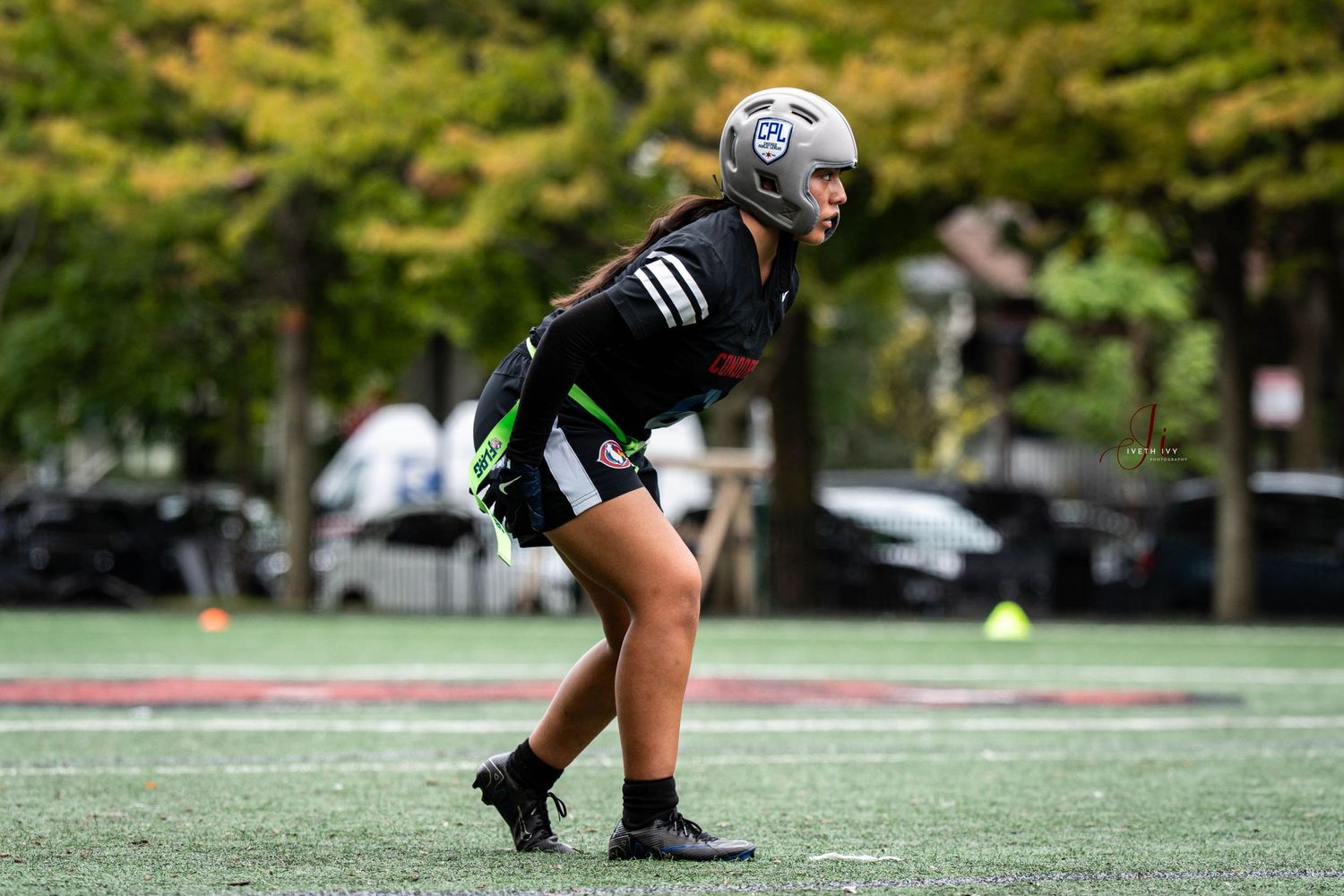 Football player's legs and feet wearing white cleats execute running motions on artificial turf field during practice.