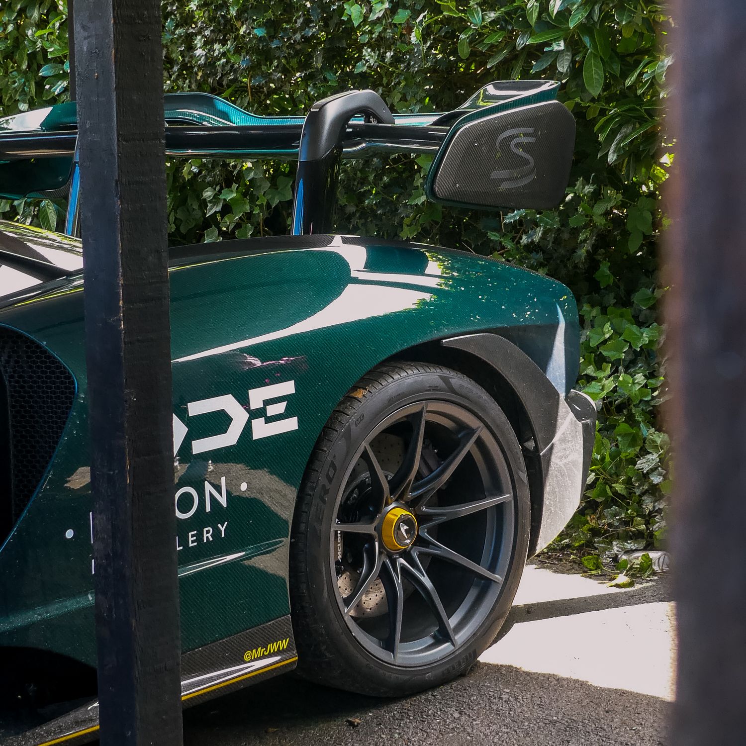 Close-up view of a green race car's wheel and body panel featuring sleek aerodynamic design and custom alloy wheels.