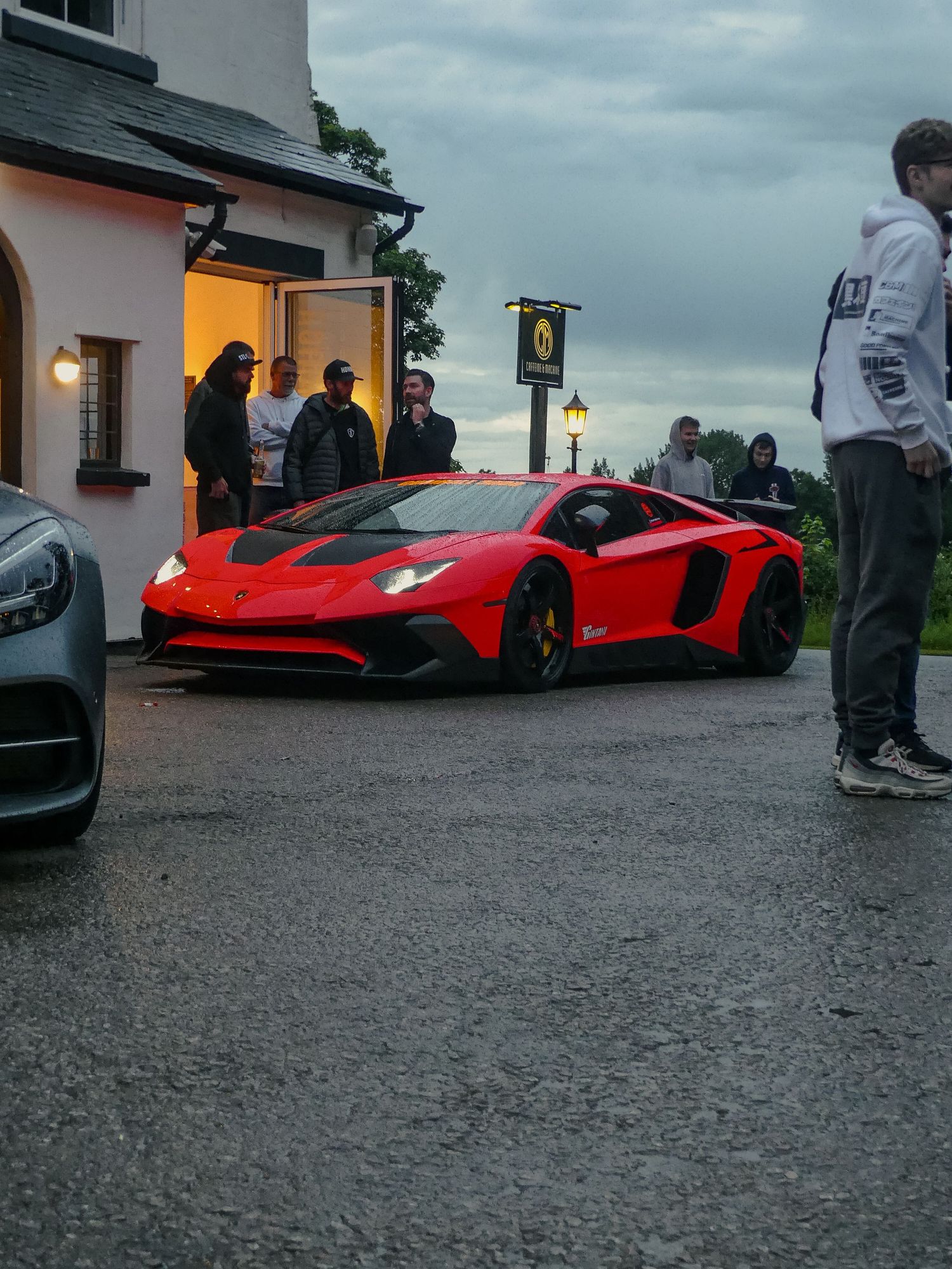 Red supercars parked outside building at dusk with dramatic lighting.