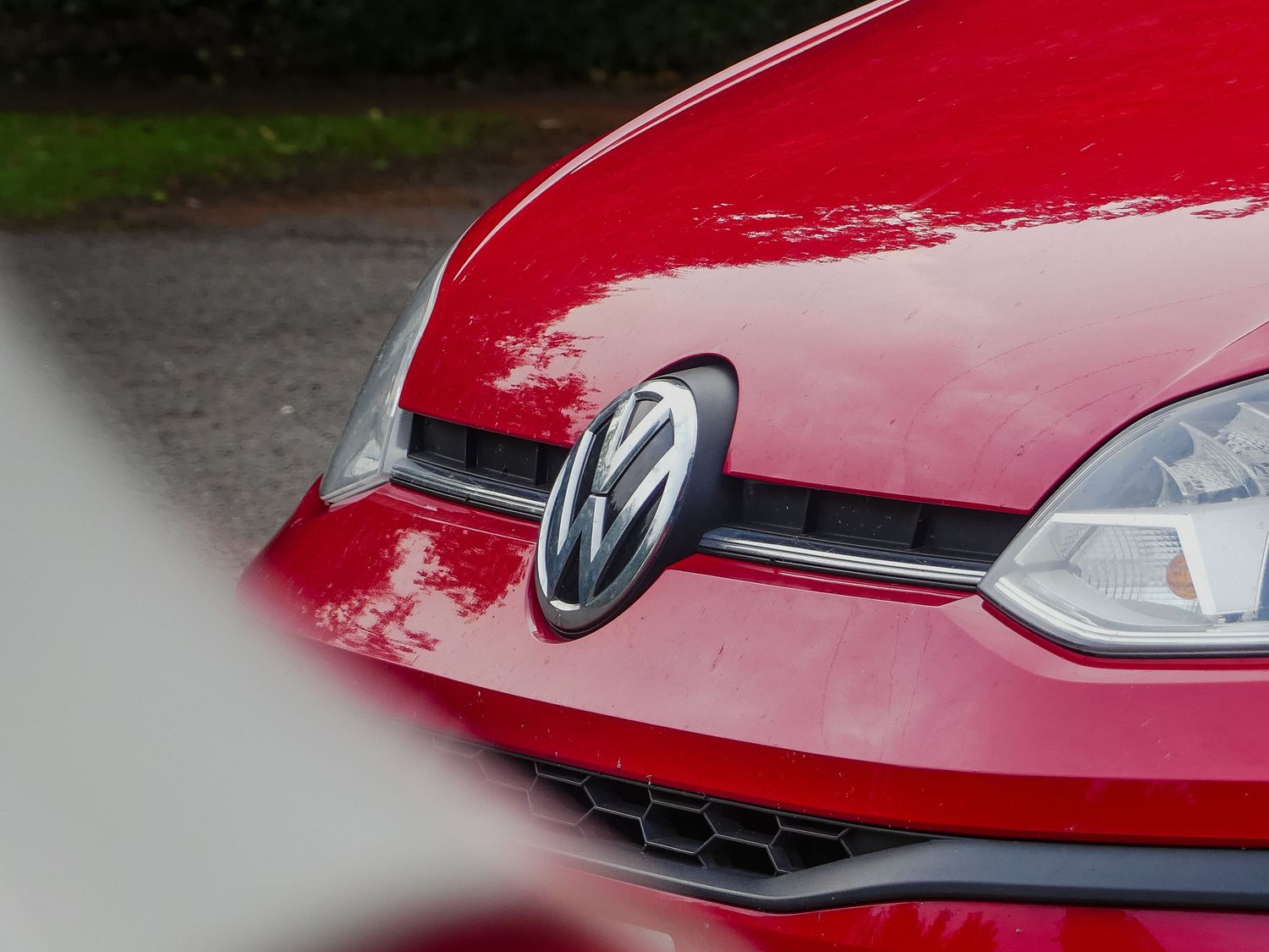 Close-up view of a red Volkswagen car's front grille showing the VW logo and headlight detail.