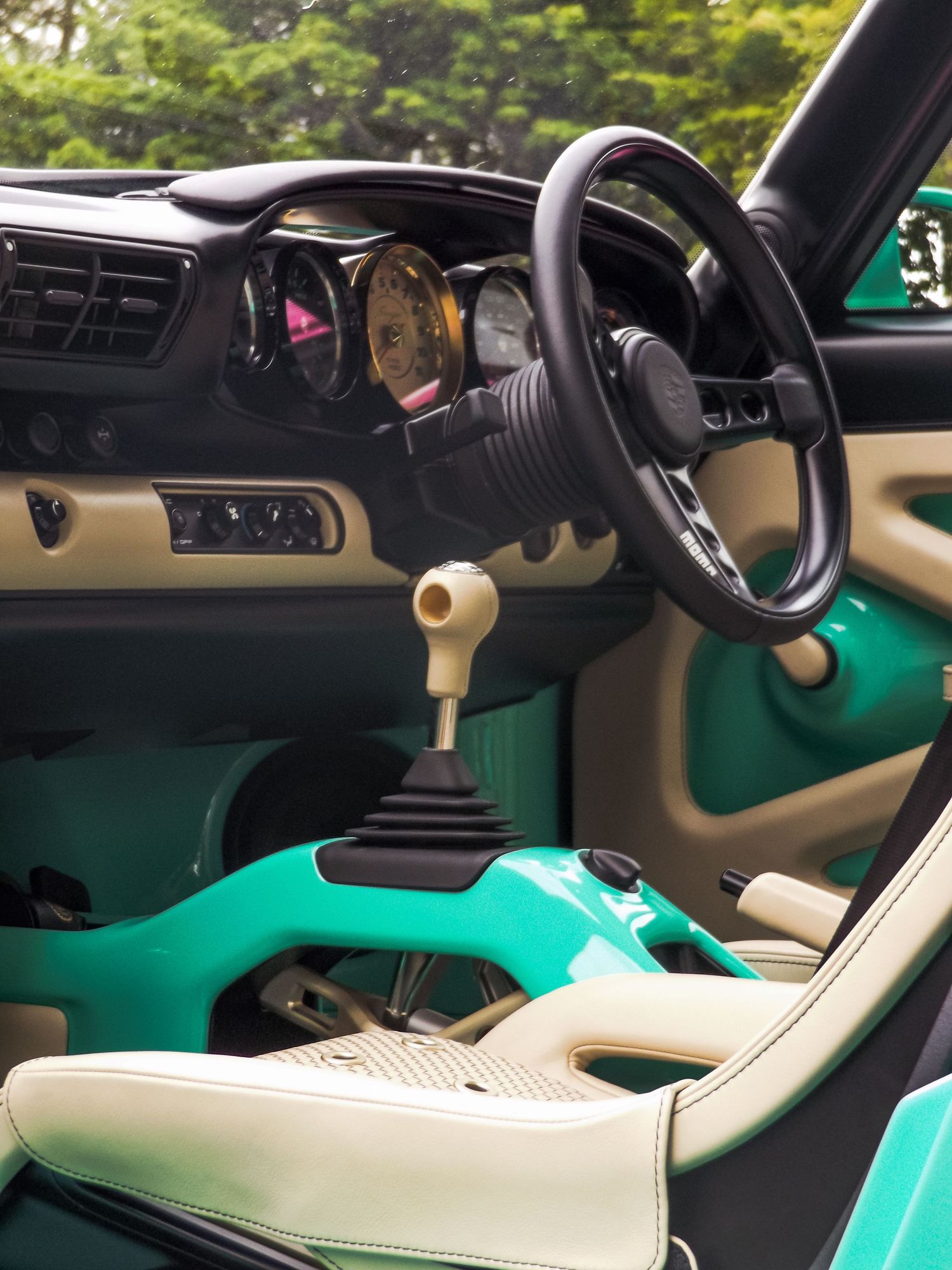 Modern luxury car interior featuring teal accents and cream leather upholstery.