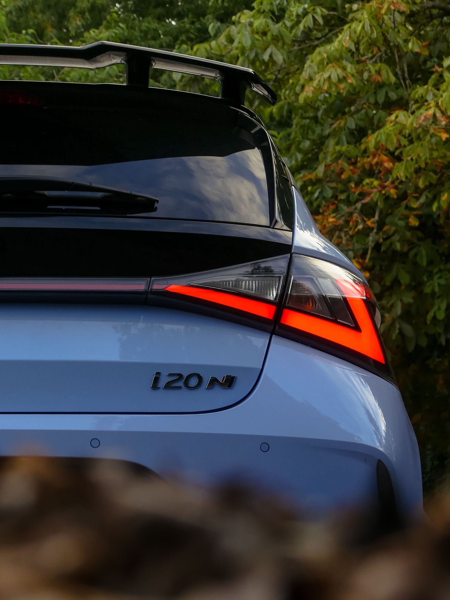 Close-up detail view of a white Hyundai IONIQ N's sleek silhouette and modern rear LED taillights against foliage.