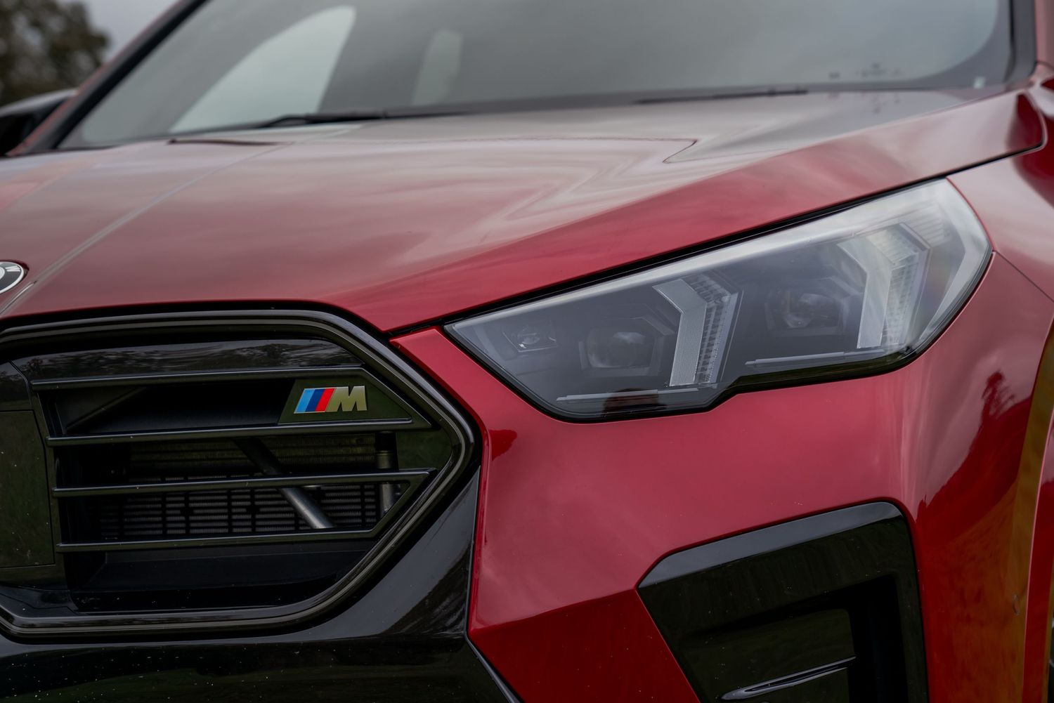 Close-up shots of a red BMW M4's exterior details showing grille, headlights and body panels.