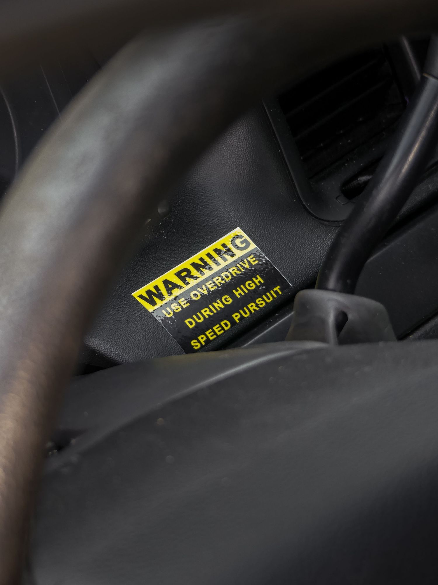 Yellow warning sticker inside a vehicle's dark interior.