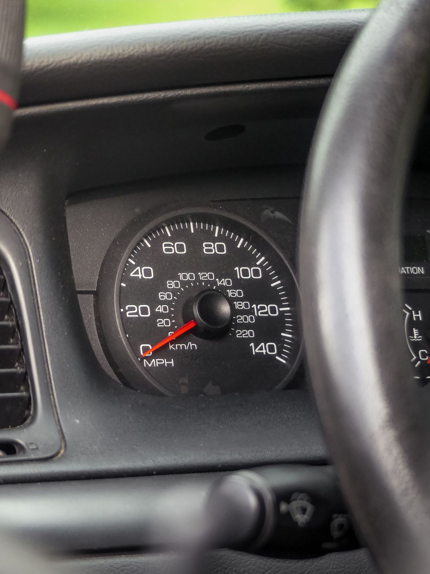 Close-up view of a black car speedometer dashboard showing analog MPH gauge with needle at zero position.