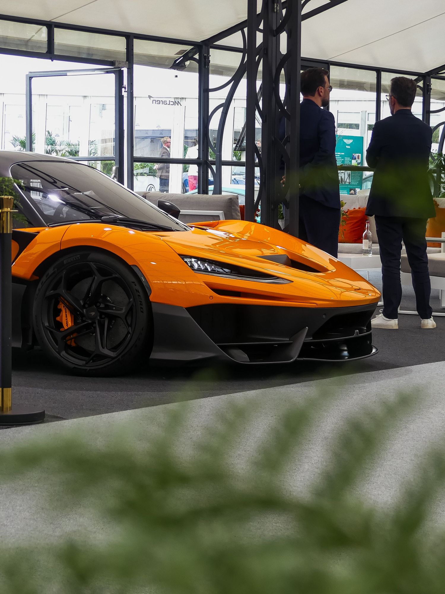 Row of stunning orange McLaren supercars on display in a modern showroom with dramatic low angle perspective.