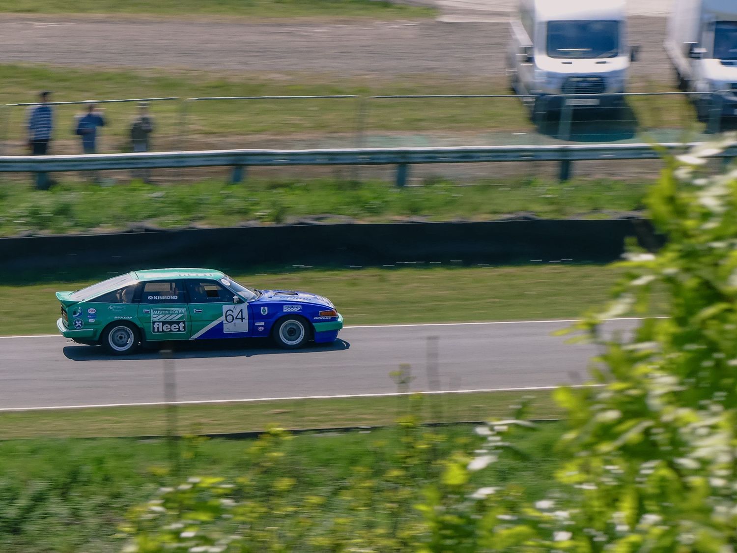 Teal race car in motion on a racetrack captured with motion blur.