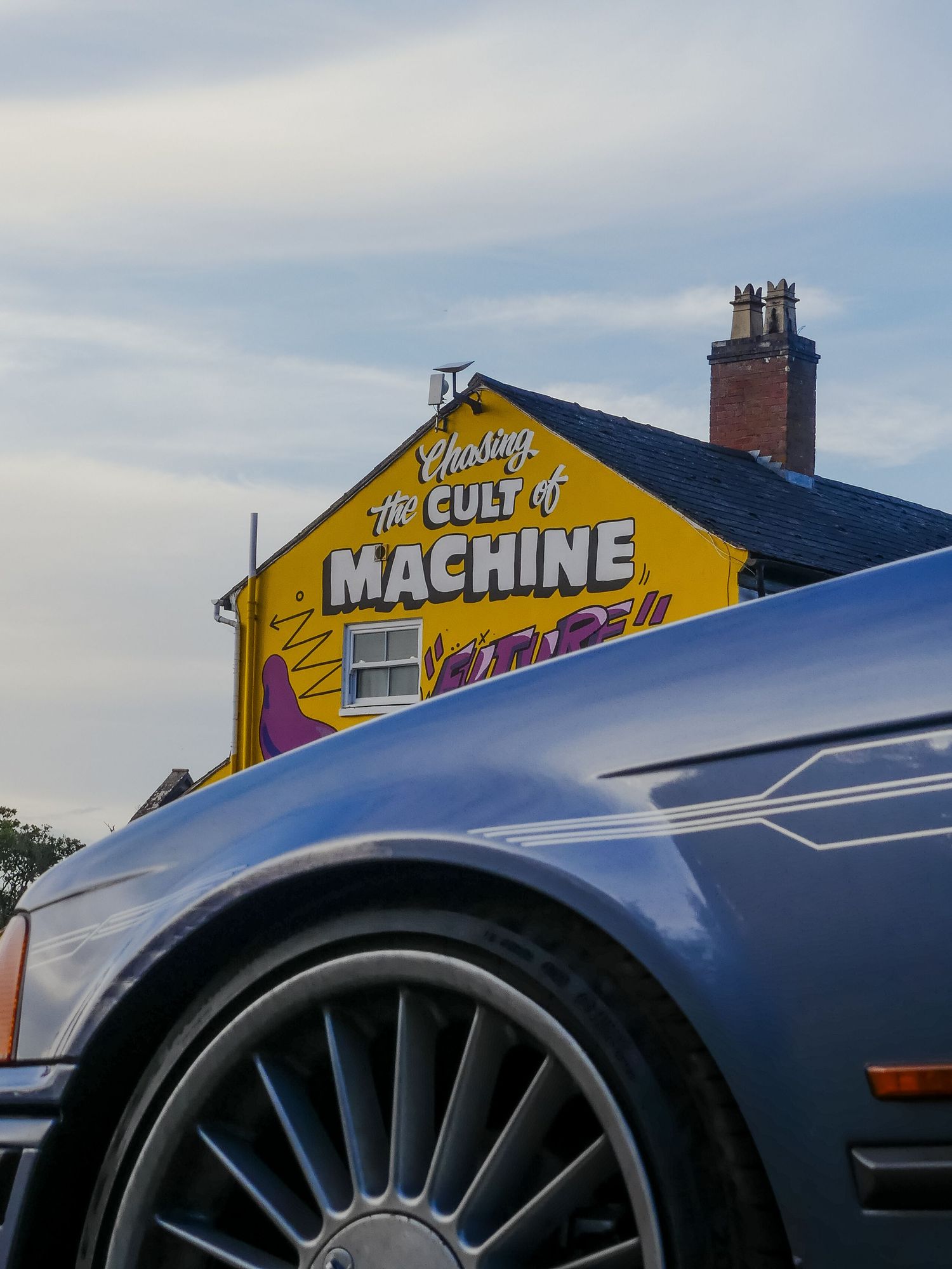 A series of close-up shots showing a blue car's wheel and yellow building with 'Machine' text on its facade.