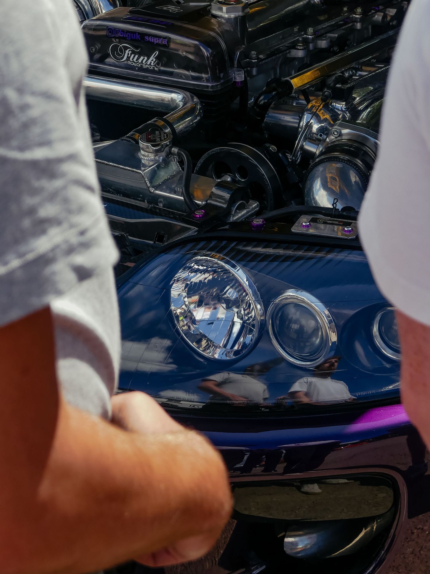 Detailed view of classic car engine components and headlights with chrome detailing.