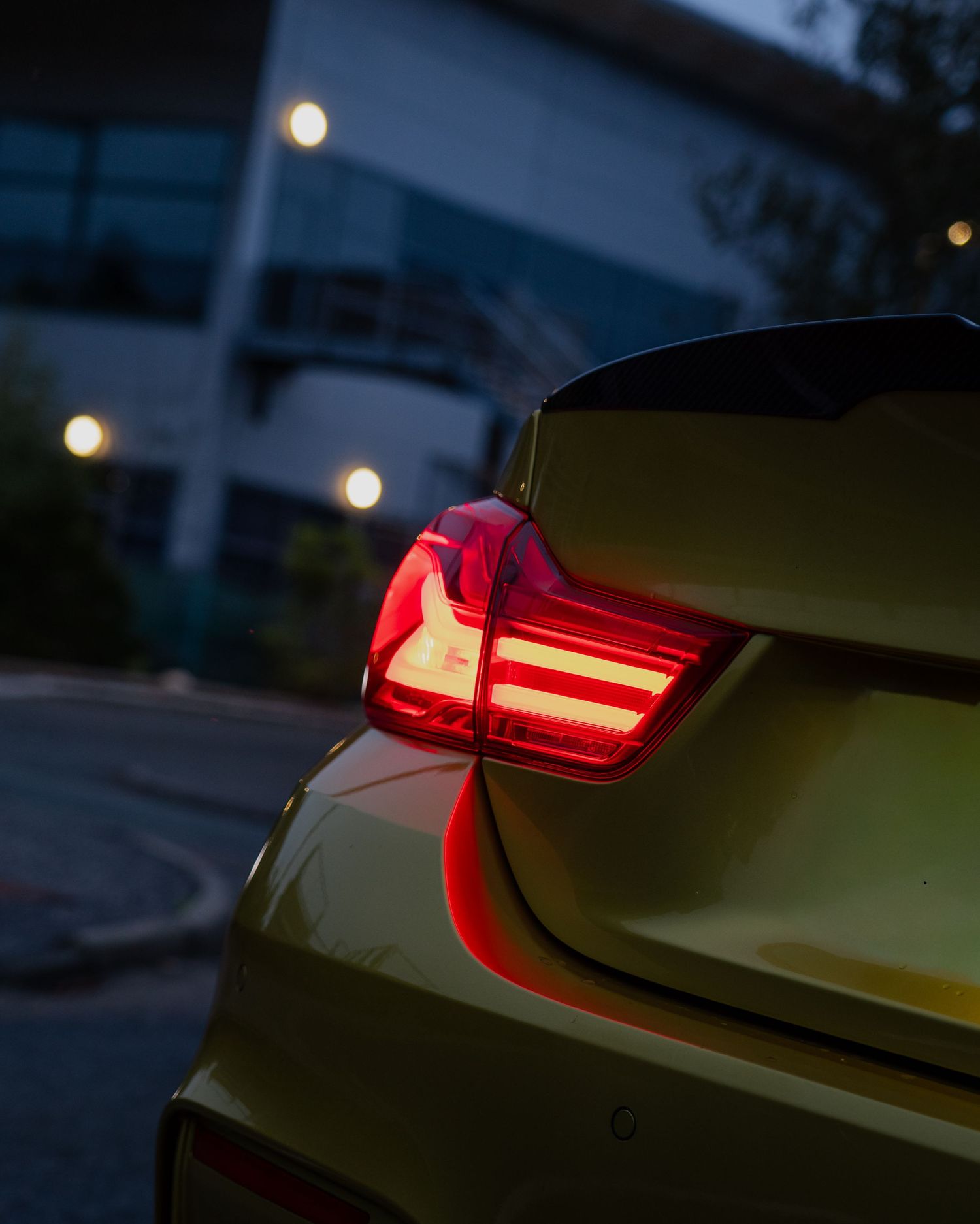 Close-up view of modern car taillights glowing red in low light conditions.