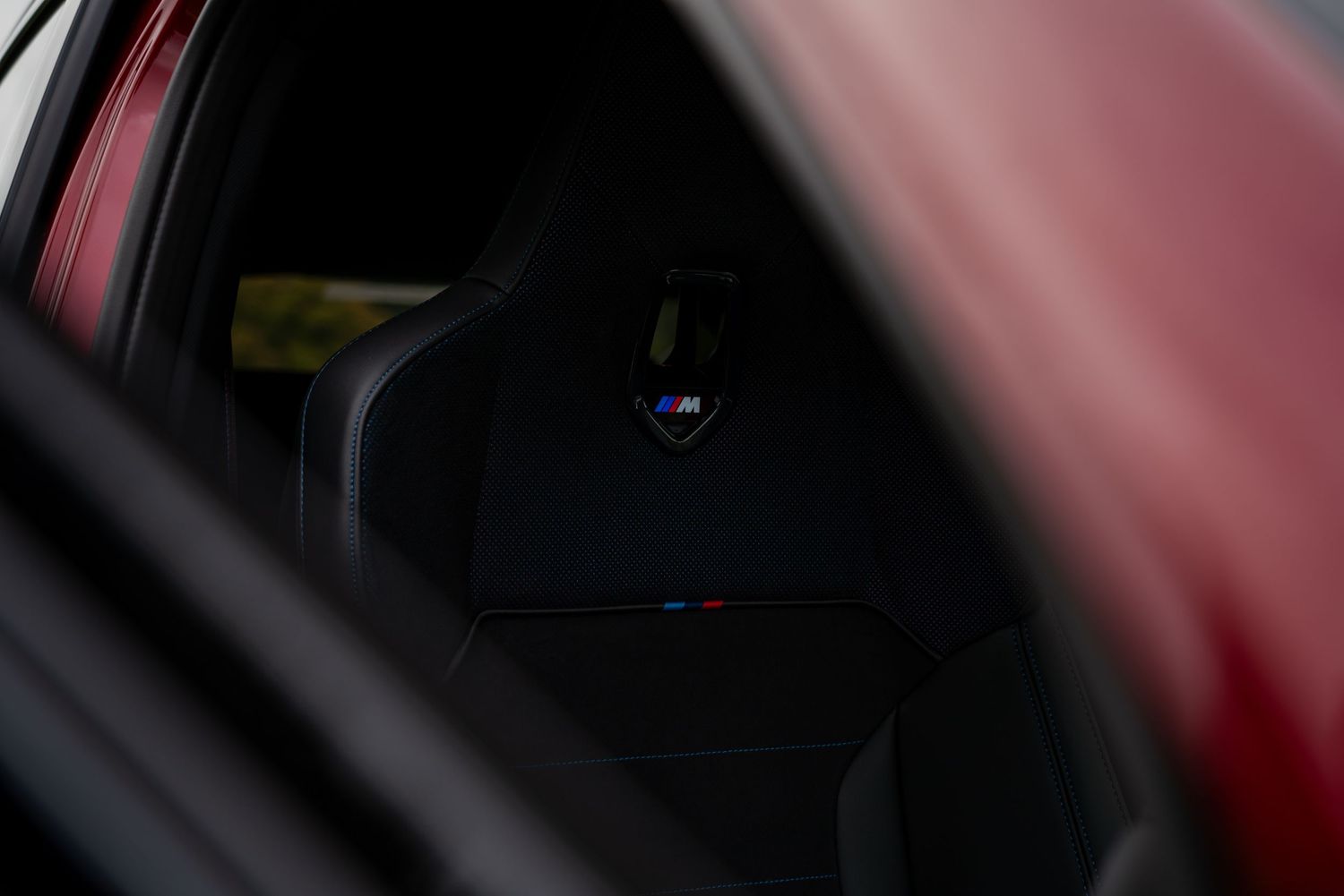 A red car interior with dark leather seats and dashboard illuminated by ambient lighting.