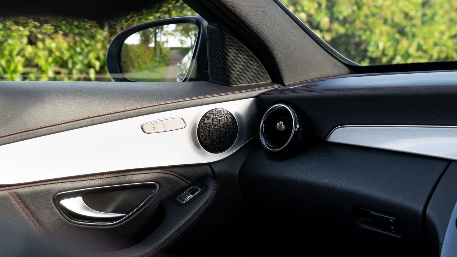 Close-up of a Mercedes-Benz car door interior panel featuring a sleek speaker and chrome trim detail.