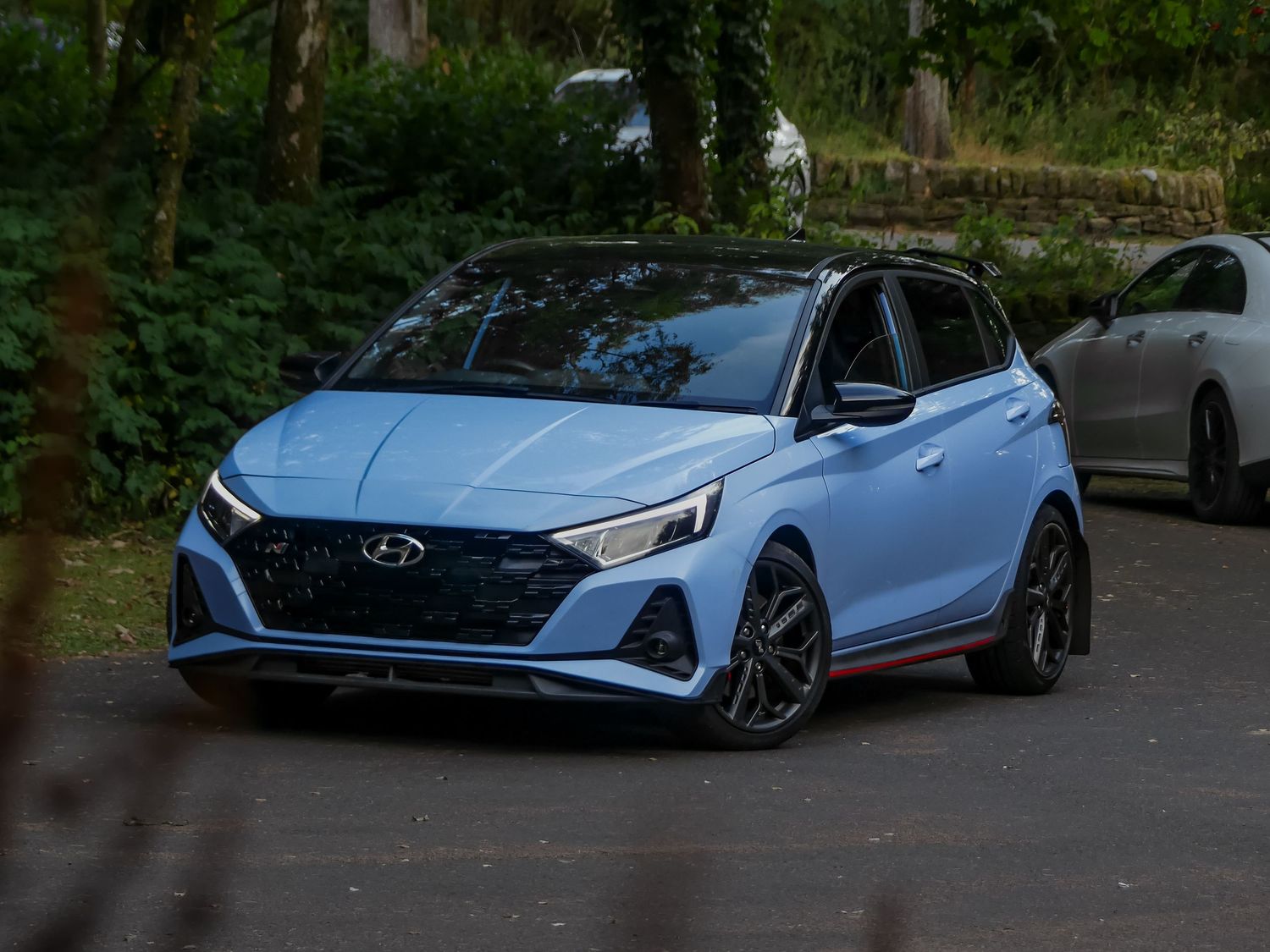 Four blue Hyundai Elantra N cars parked in a row showcase the sporty design and performance features.