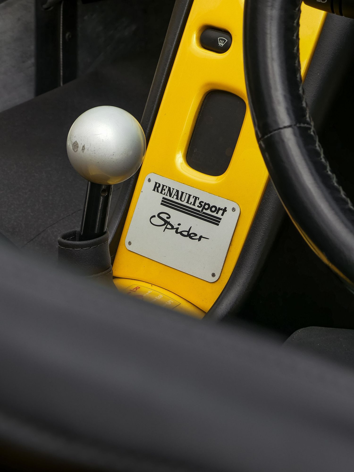 Close-up view of yellow and black interior car parts showing buttons and control panel details in sporty design style.