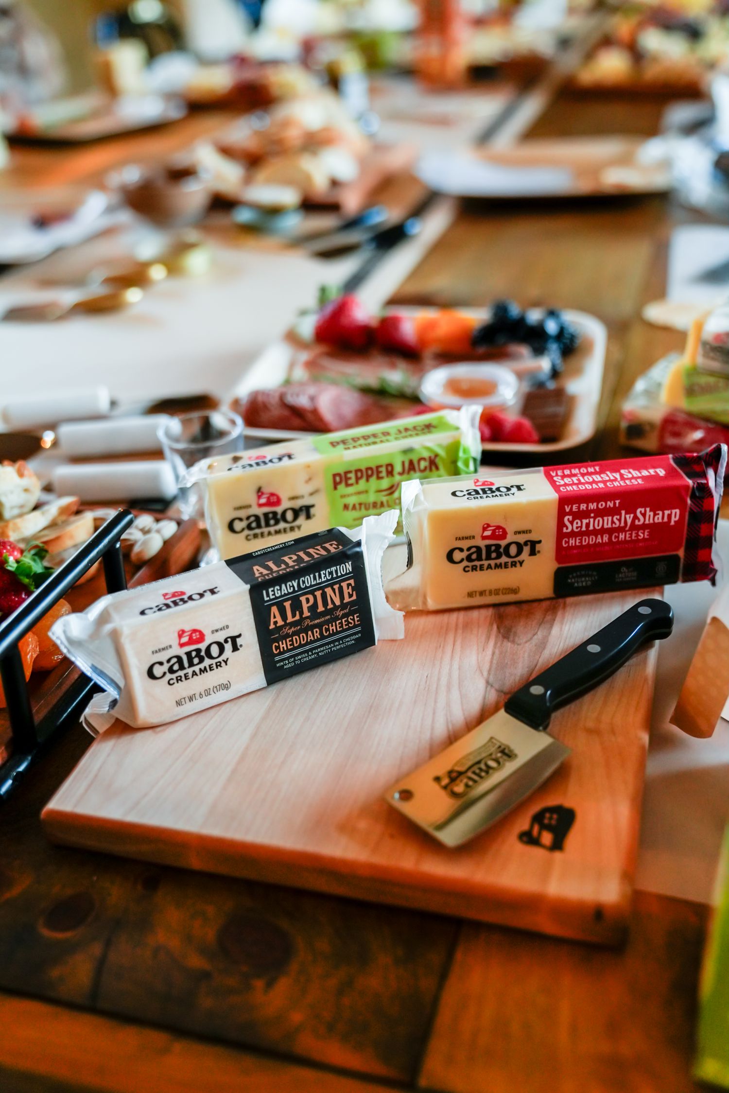 Cabot cheese blocks and tasting supplies arranged on a wooden cutting board.