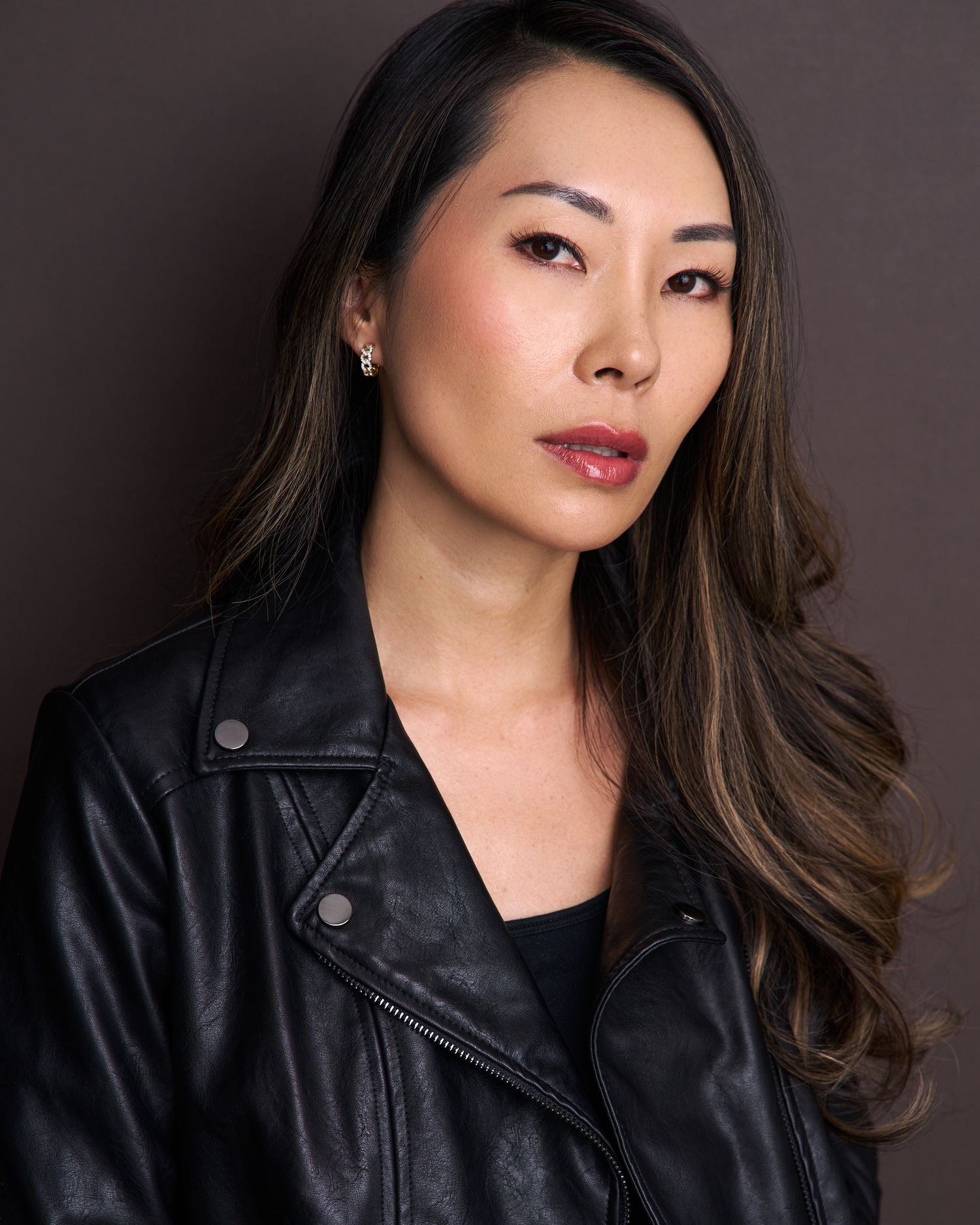 Professional headshot series showing warm expressions against dark background wearing black leather jacket.