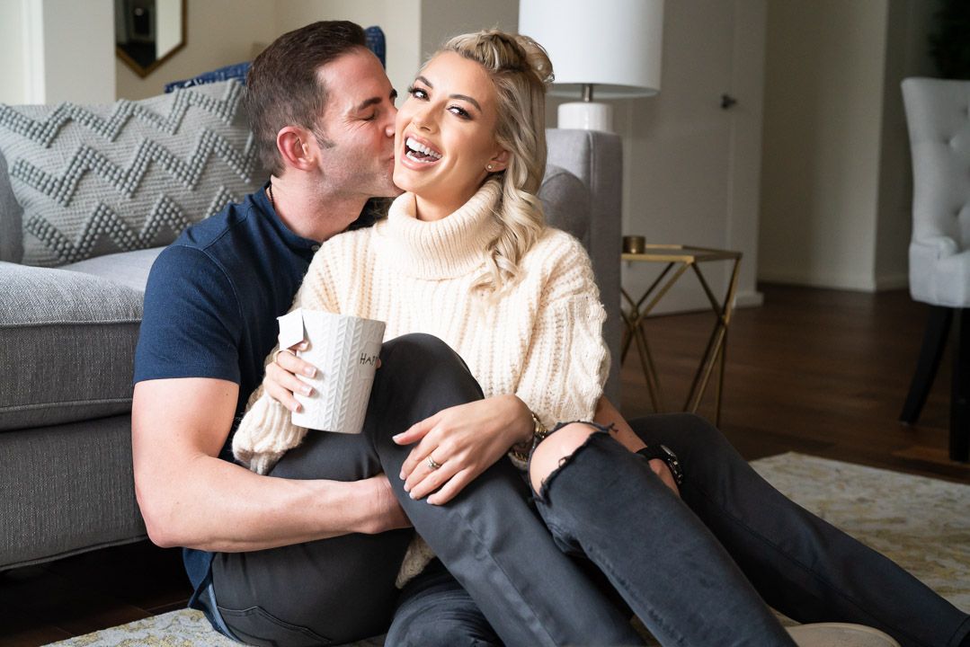 Tarek El Moussa and Heather Rae El Moussa sharing intimate moments on a cozy gray couch in a bright living room setting for Us Weekly