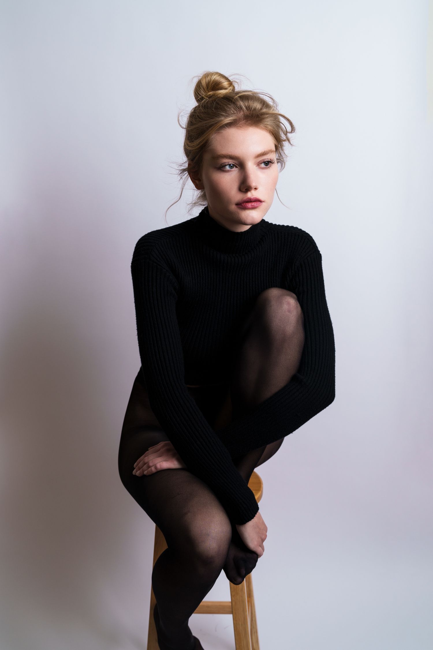 Studio fashion portrait series showing poses in black turtleneck against light background.